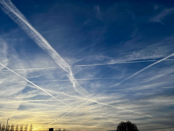 Traînées de condensation laissées par les avions dans un ciel bleu intense au lever du soleil